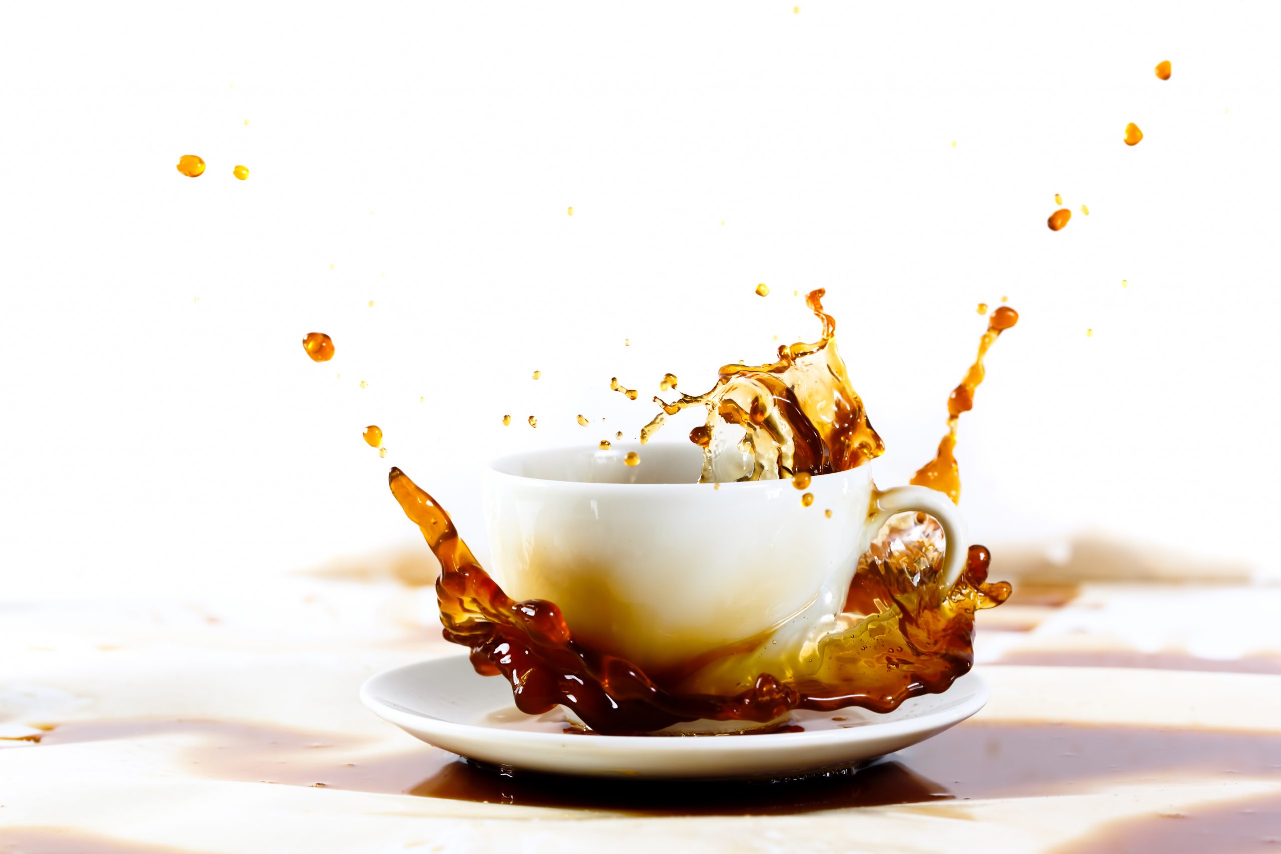 Cup of coffee creating splash. White background, coffee stains. Coffee break, breakfast concept.