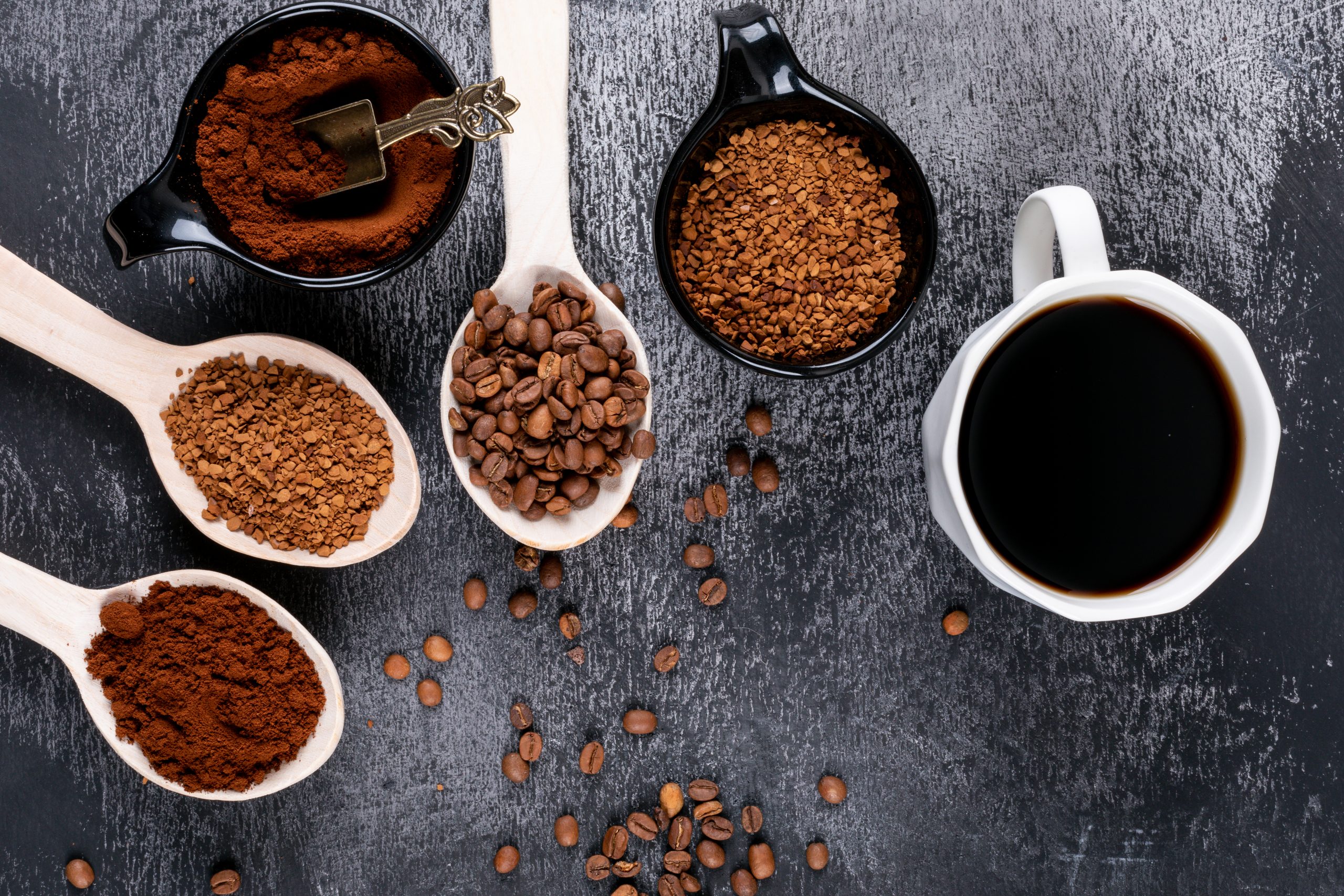 top view instant coffee in wooden spoons and coffee cup on dark background
